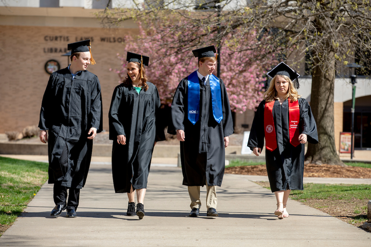 People wearing graduation gowns and caps walking.