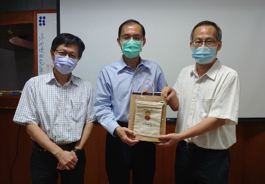 Man receiving a certificate of appreciation from two men