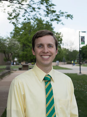 Man wearing a yellow shirt and green tie.