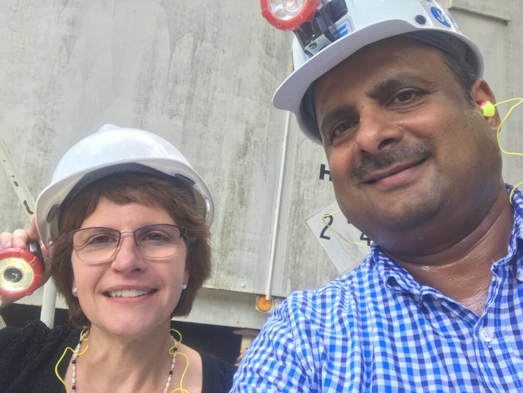 Two people wearing hard hats and ear protection.