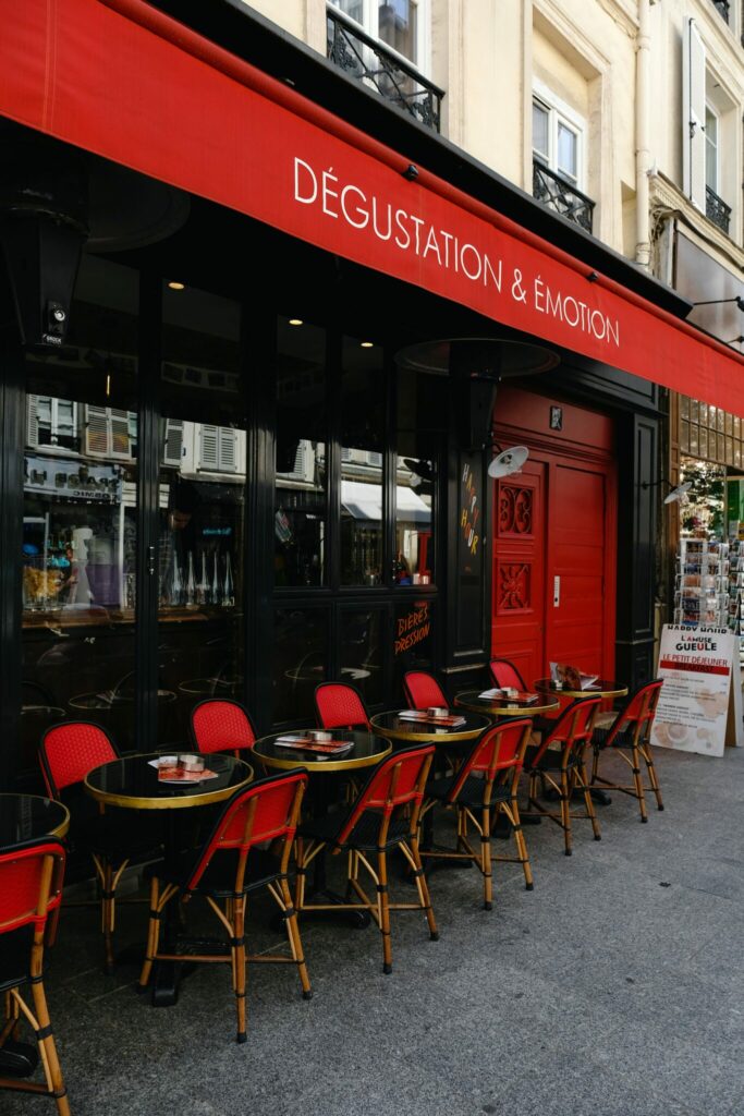Street side cafe with red awning and red chairs. The words "Degustation & Emotion" on the awning.