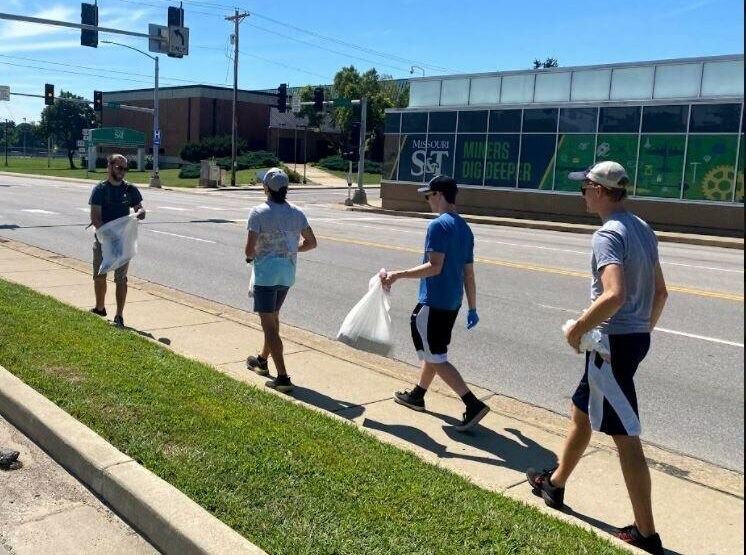 Students walking along the road picking up trash.