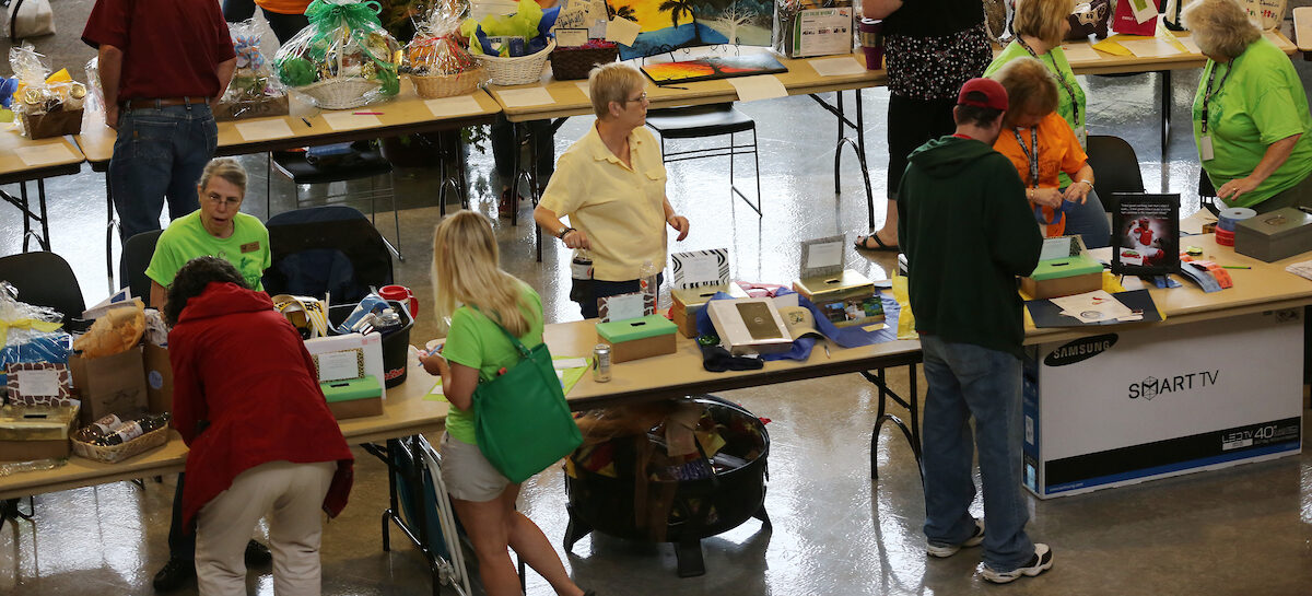 People standing around tables filled with raffle items.