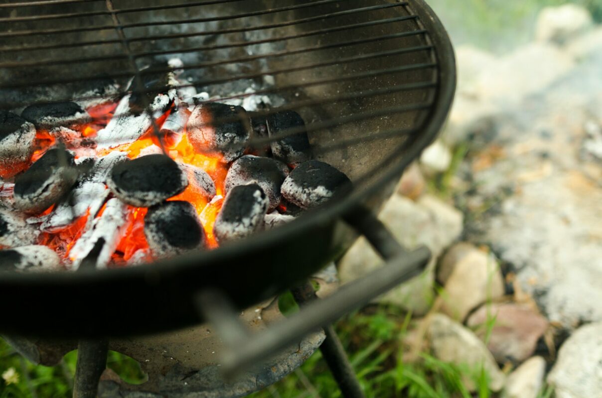 A photo of a grill with charcoal on fire.