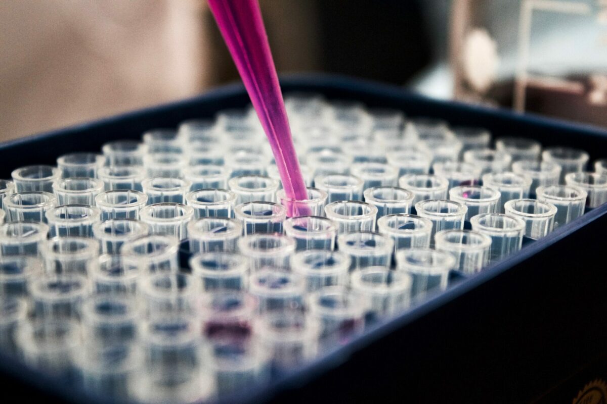A photo of test tubes with a pink liquid being poured.