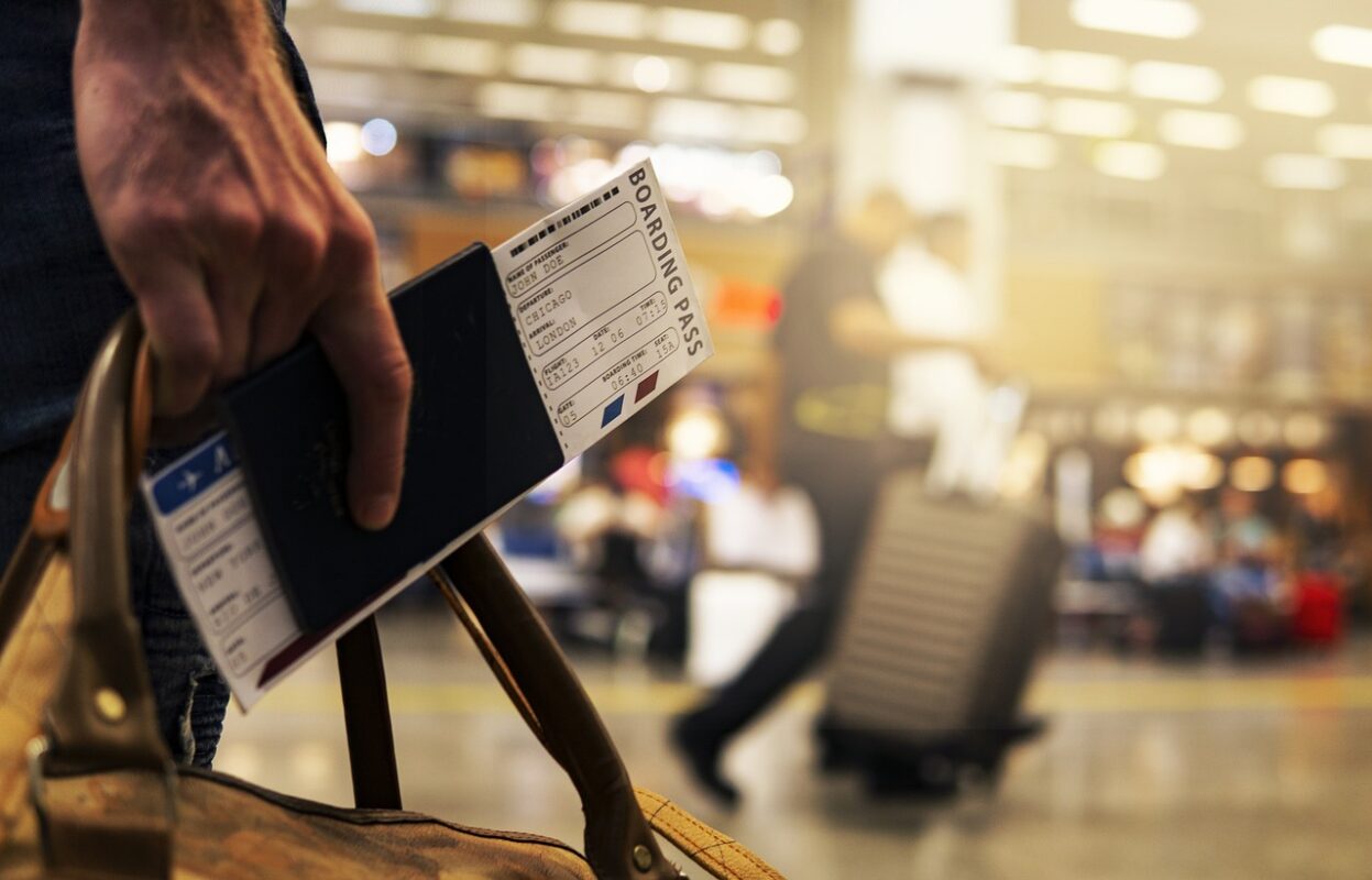 A hand holding a passport with a airline ticket.