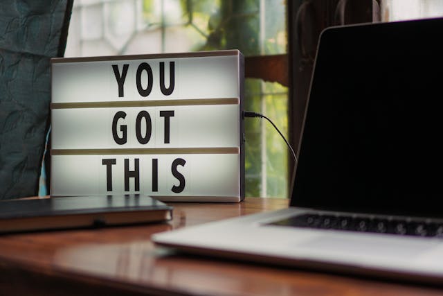 Letterboard with "You got this spelled out, next to laptop.