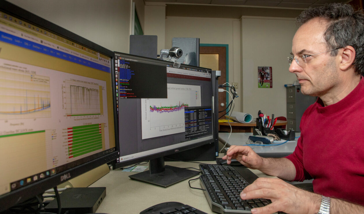 A man working on a computer with charts and graphs displayed.