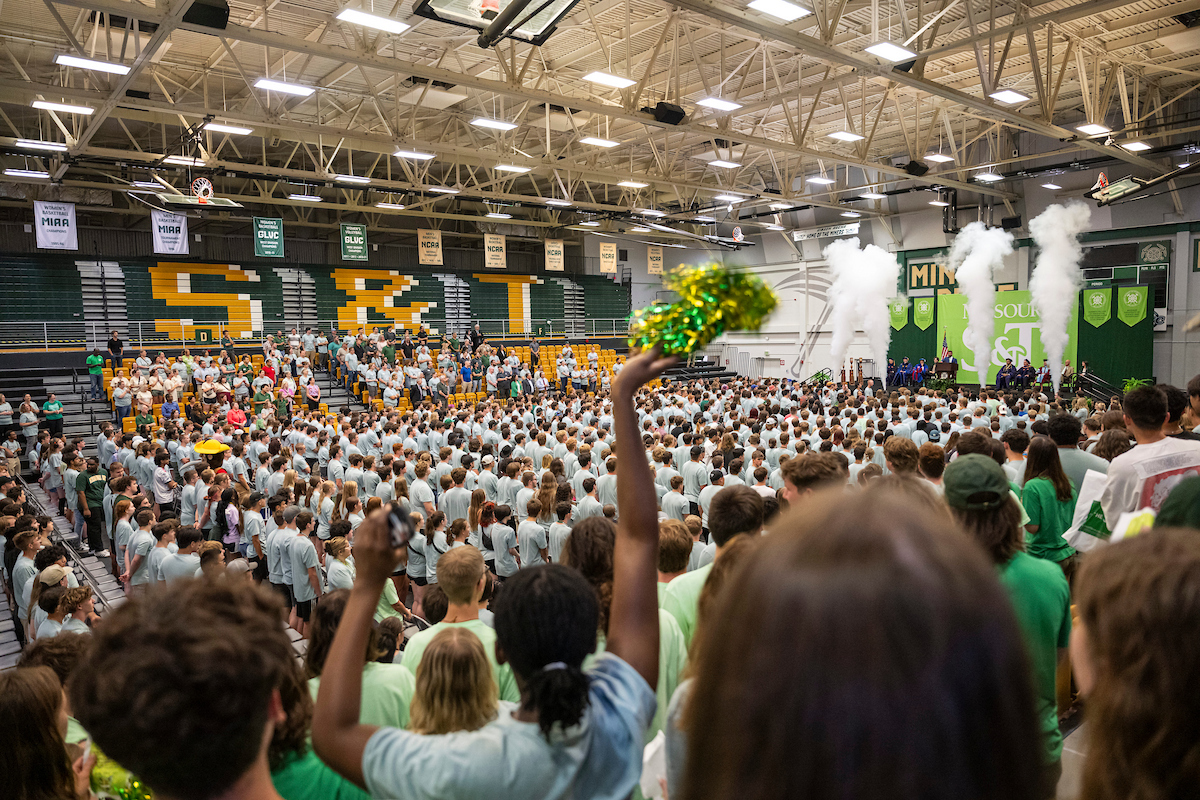 New students fill a gymnasium celebrating the start of their college career.