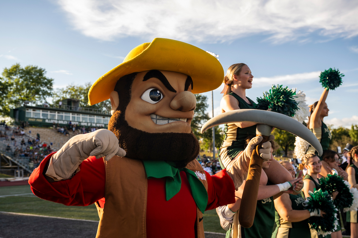 The Miners mascot cheers alongside a row of cheerleaders.