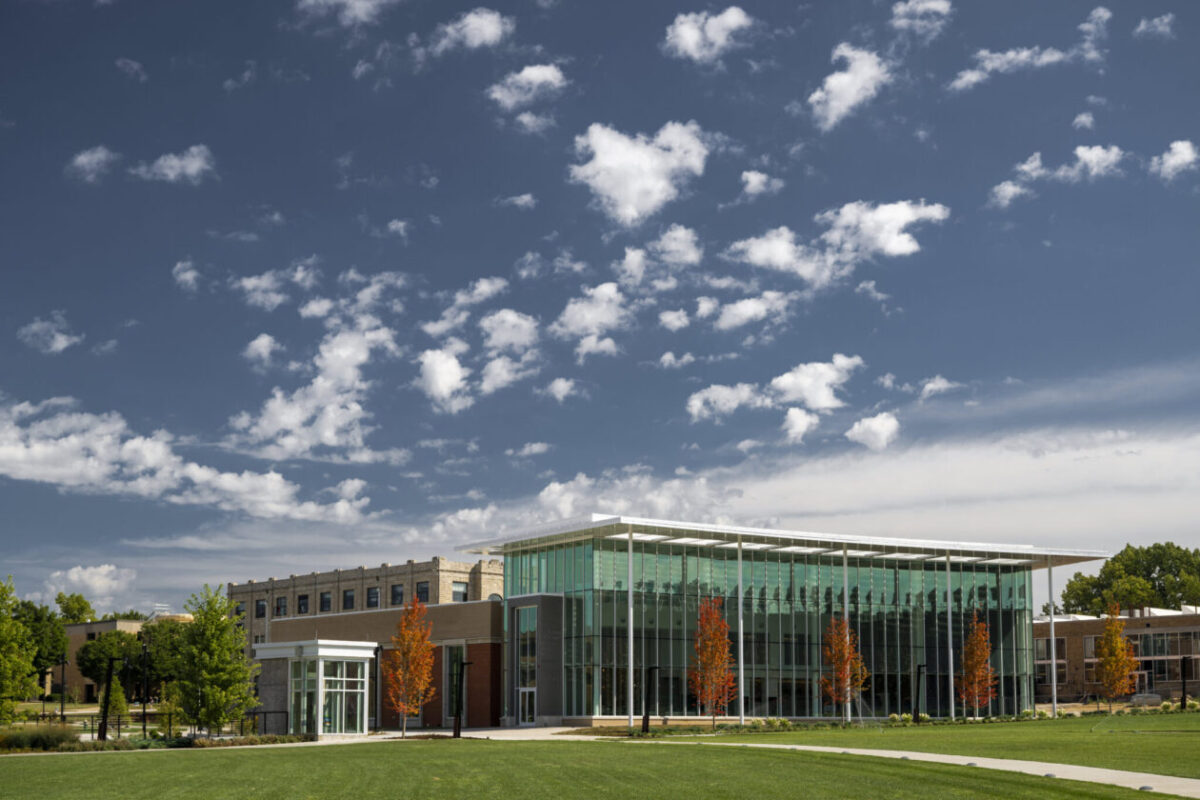 The southwest corner of the Welcome Center, which has a glass three story front with five pillars and ornamental trees in front.
