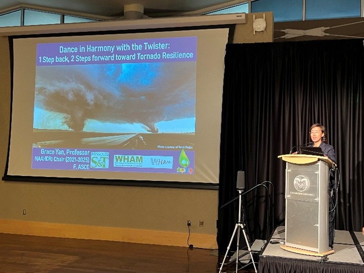 Grace stands at a podium next to a presentation on a projector screen.
