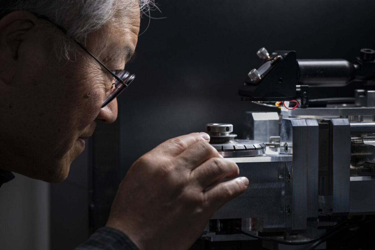 A man with glasses looks closely at a piece of equipment.