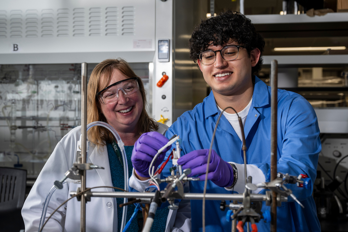 Shelley Minteer stands behind a student as they work on an experiment in her lab.