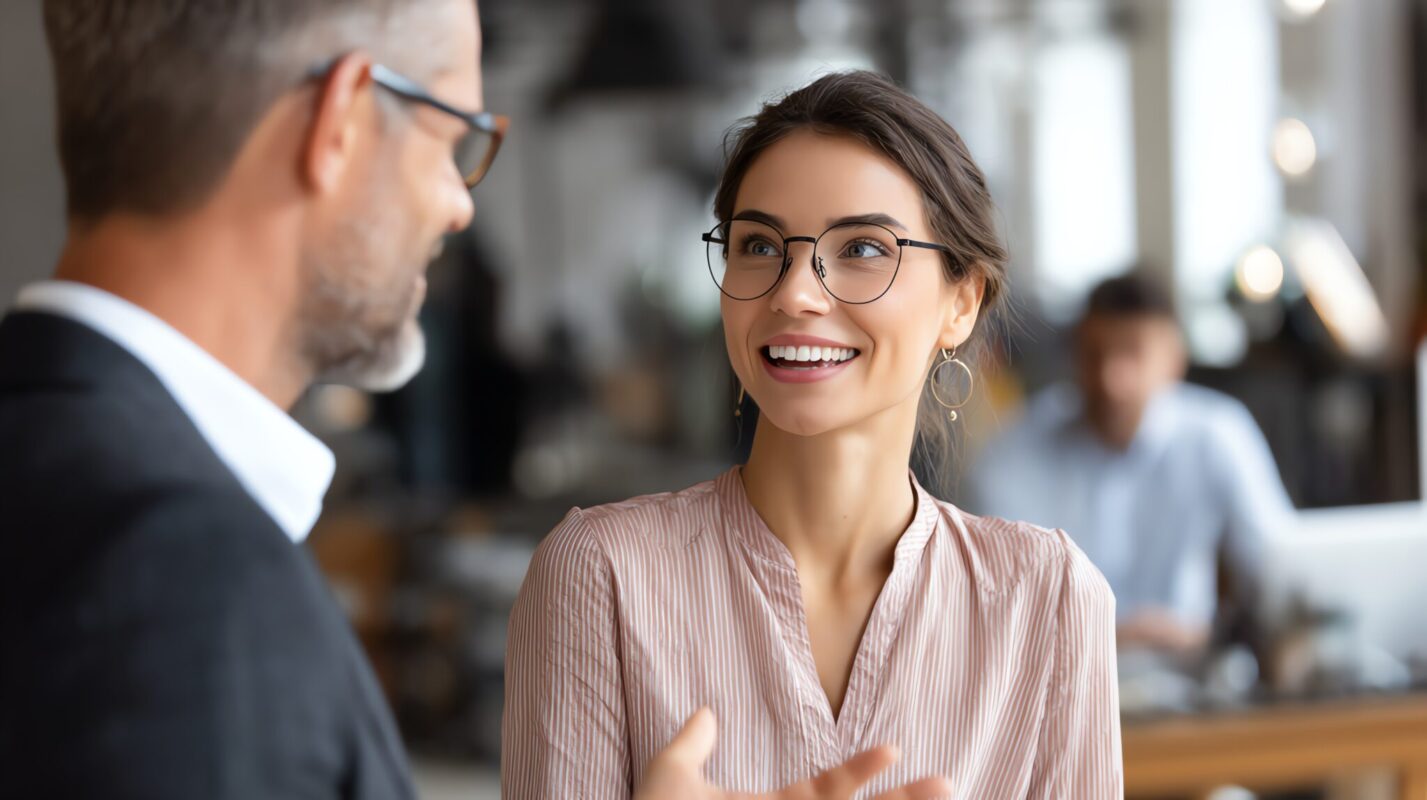 A woman smiles while chatting with a colleague.