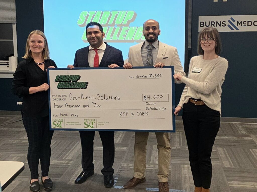 Two students hold a giant check with the program staff on each side.