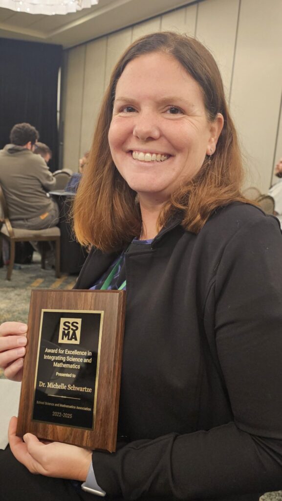 Michelle Schwartze holding a plaque from award.