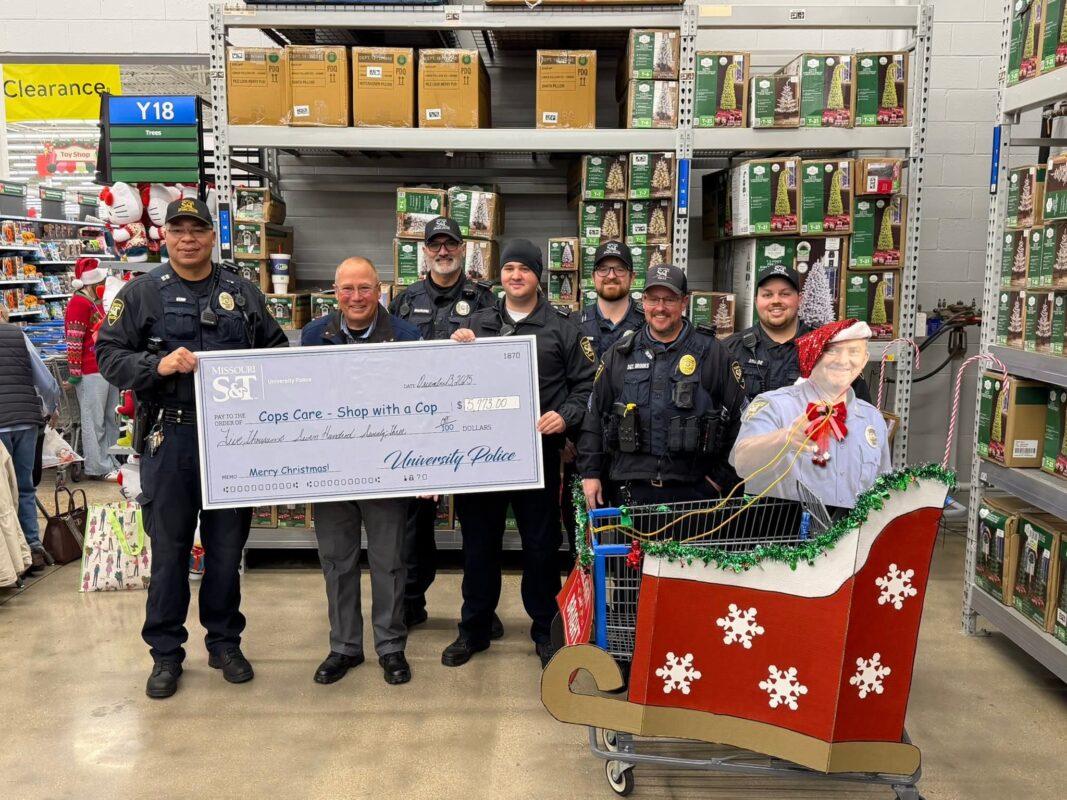 Six University Police officers present a giant check to the sheriff for the Shop with a Cop program.
