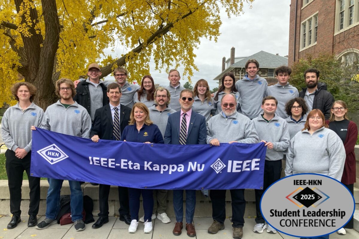 A group of students pose with a banner at the conference.
