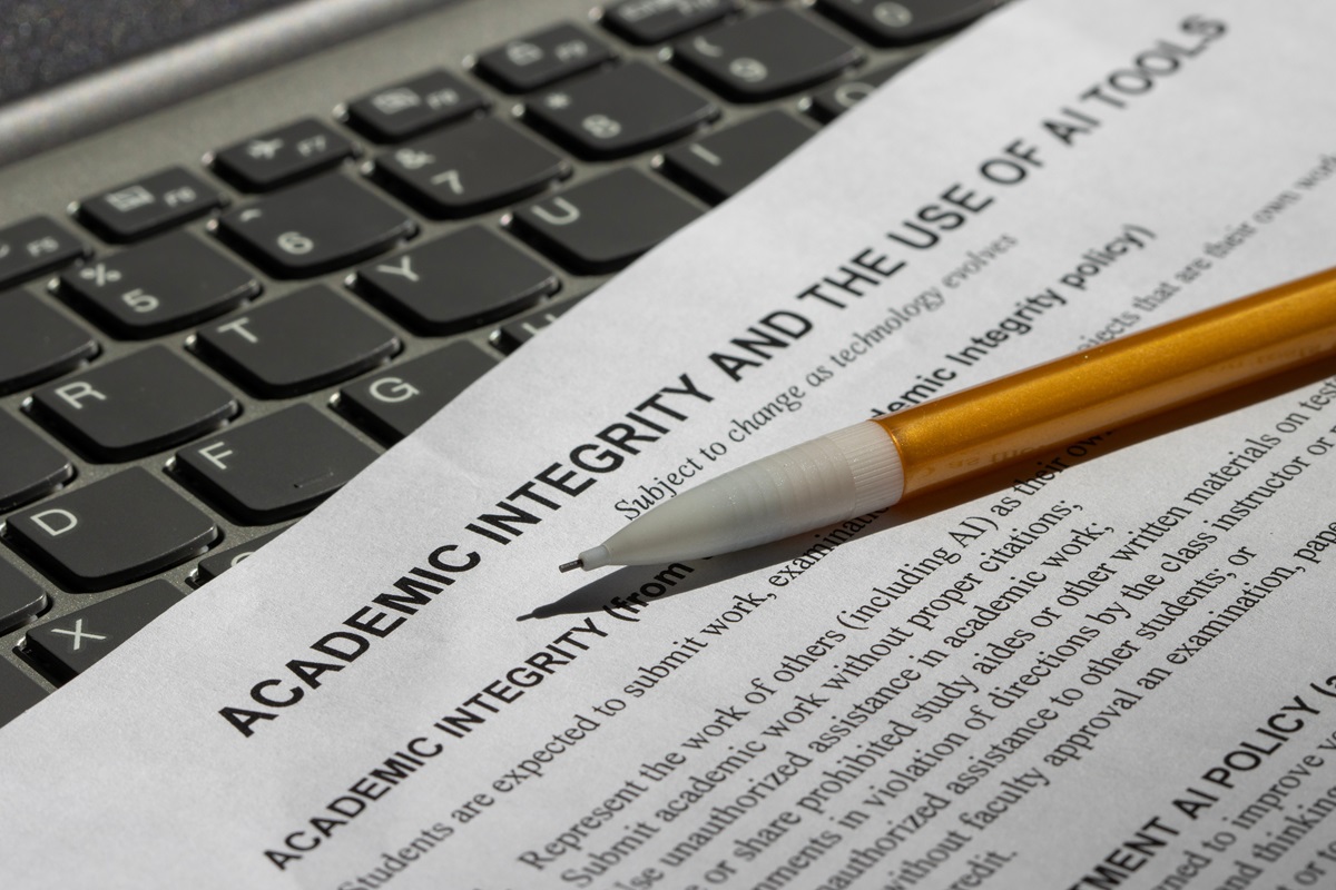 A document titled "Academic Integrity and the Use of AI Tools" rests on a keyboard, with a yellow pencil placed on top, emphasizing seriousness and focus.