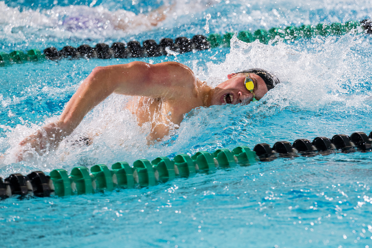 A man wearing goggles swims freestyle.