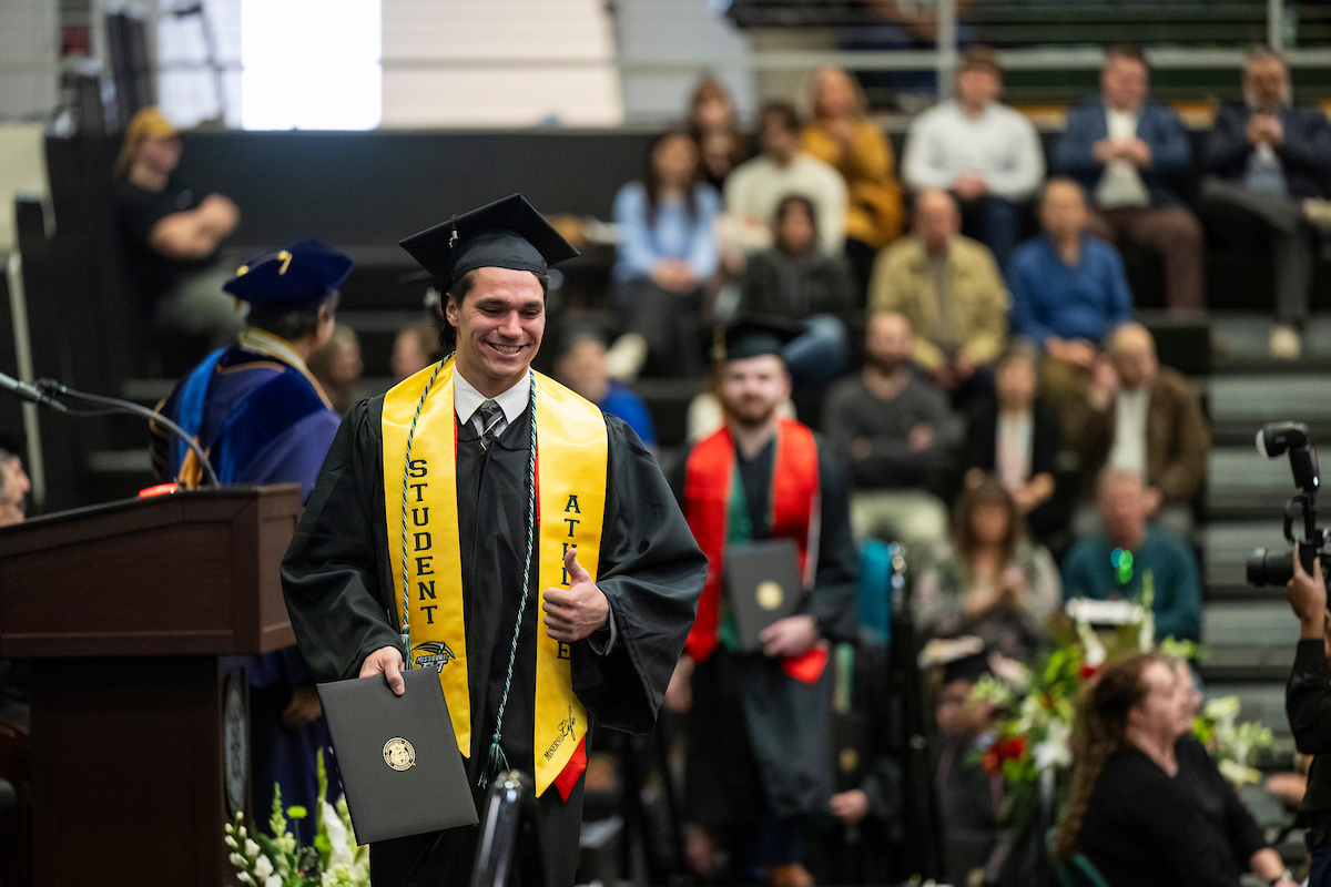 A graduate crosses the stage at commencement.