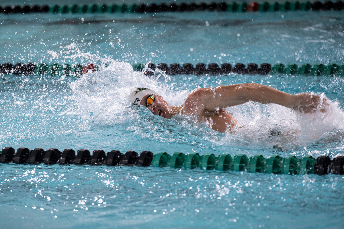 A man wearing a swim cap competes in a freestyle event.