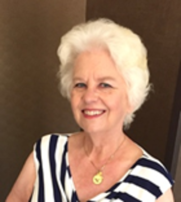 A headshot of a woman with white hair wearing a black and white striped top.