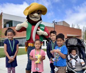 Joe Miner the mascot poses with five children outside the Innovation Lab.