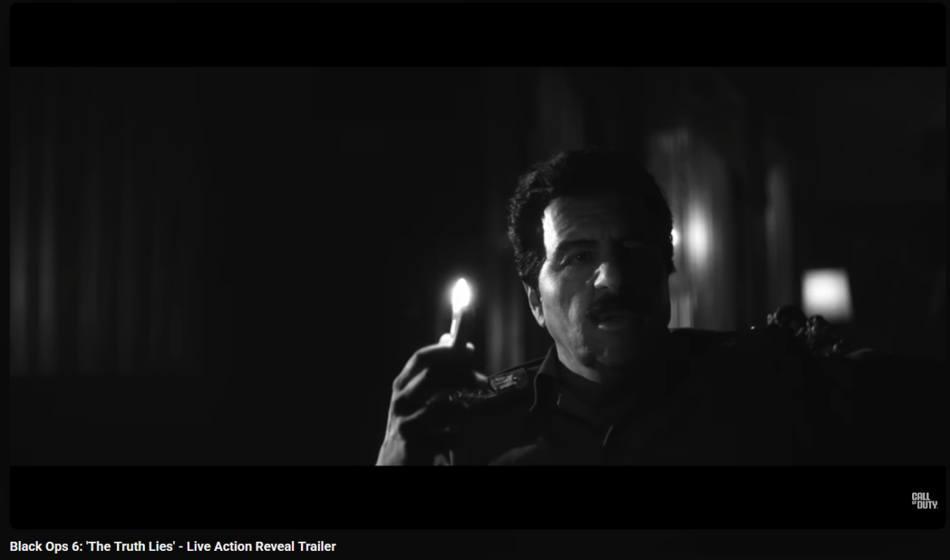 A screenshot of a video game with a man holding a match and the image is very dark.