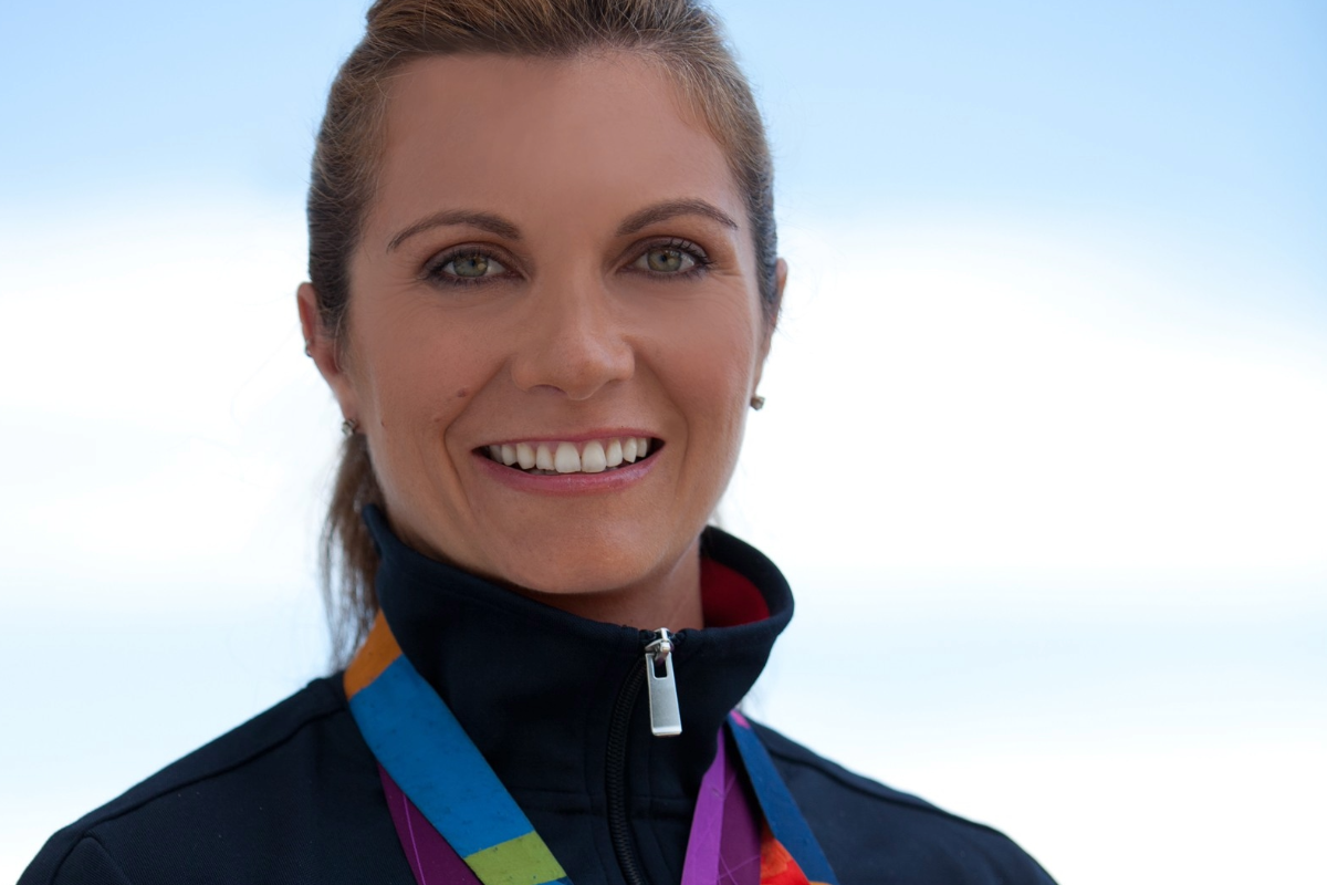A woman wearing a high neck jacket with medals hanging around her neck.