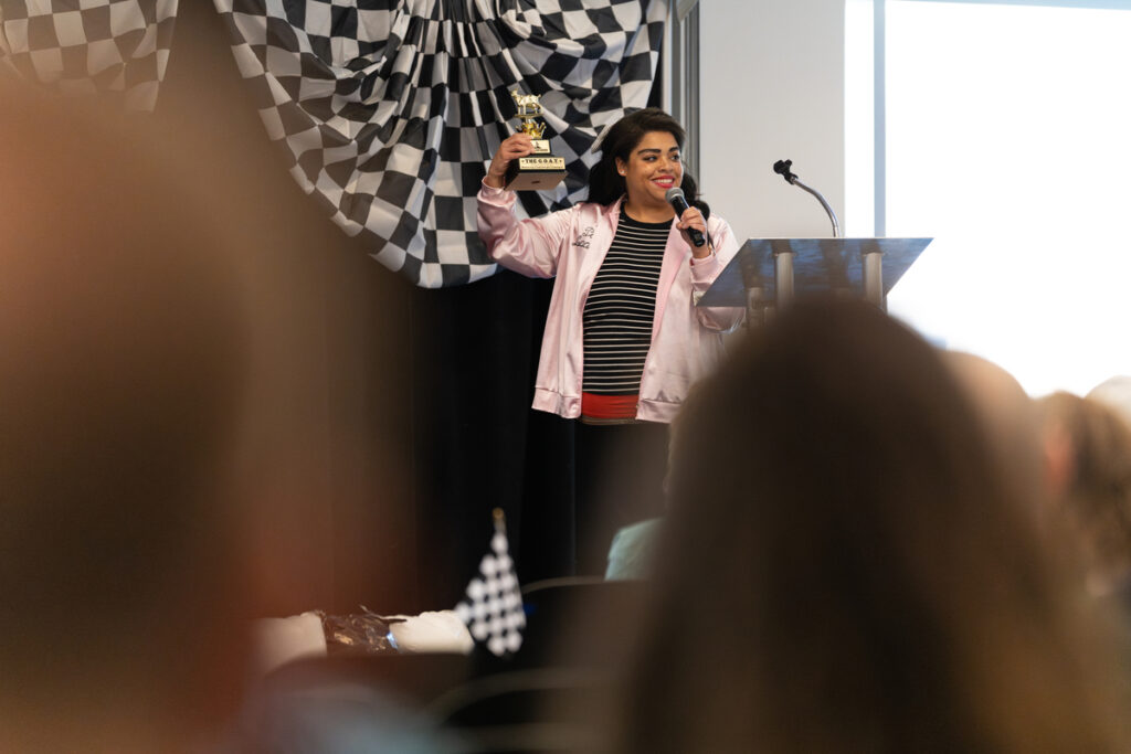Person holding a small trophy and speaking at a podium during a Missouri S\&T staff appreciation event.
