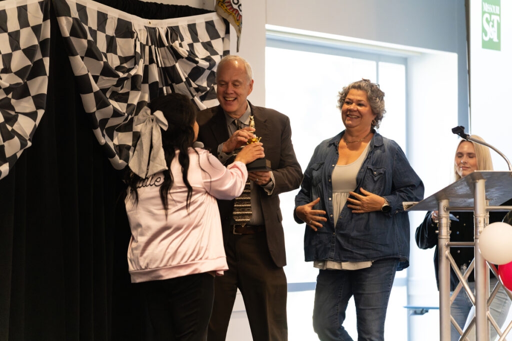 Person receiving a small trophy on stage during a Missouri S&T staff appreciation event.