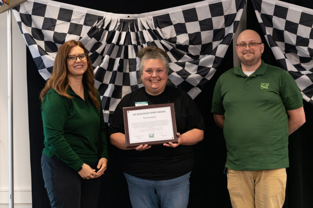 Three people on stage holding a “Jan Buhlinger Spirit Award” certificate at S&T’s Staff Appreciation Day event.