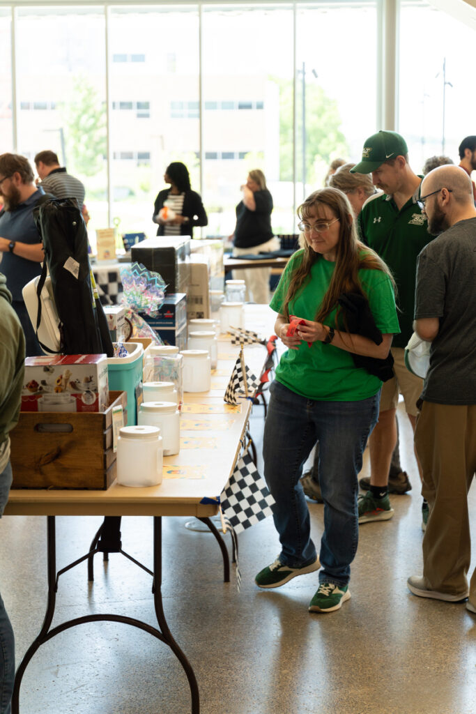 People browsing items on tables in a bright lobby during S&T’s Staff Appreciation Day event.