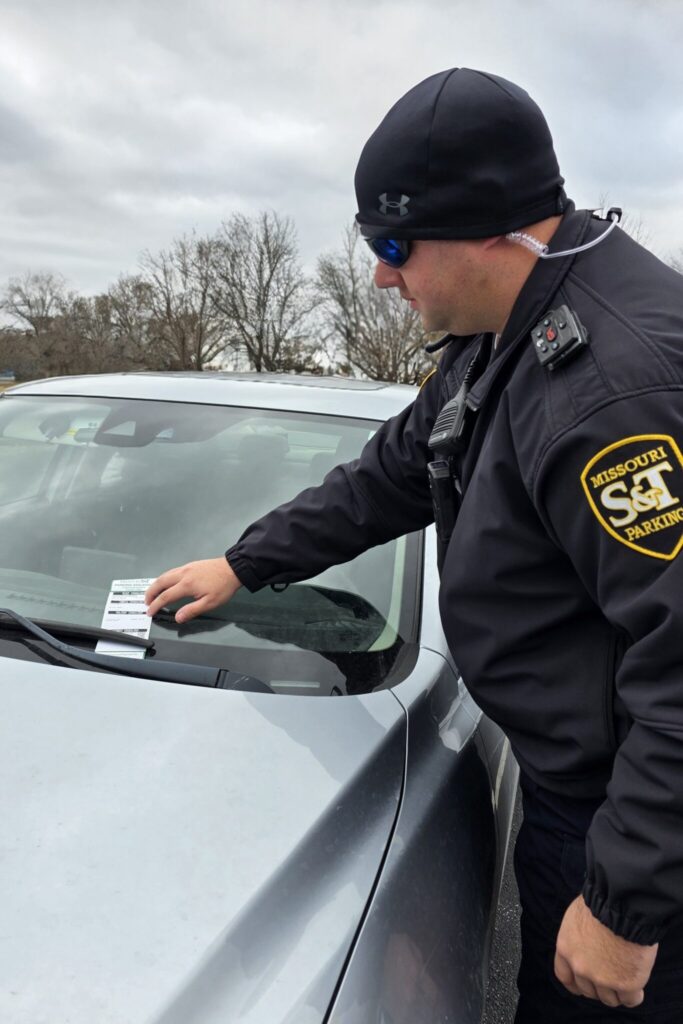 Missouri S&T parking officer places a parking citation on the windshield of a parked vehicle.