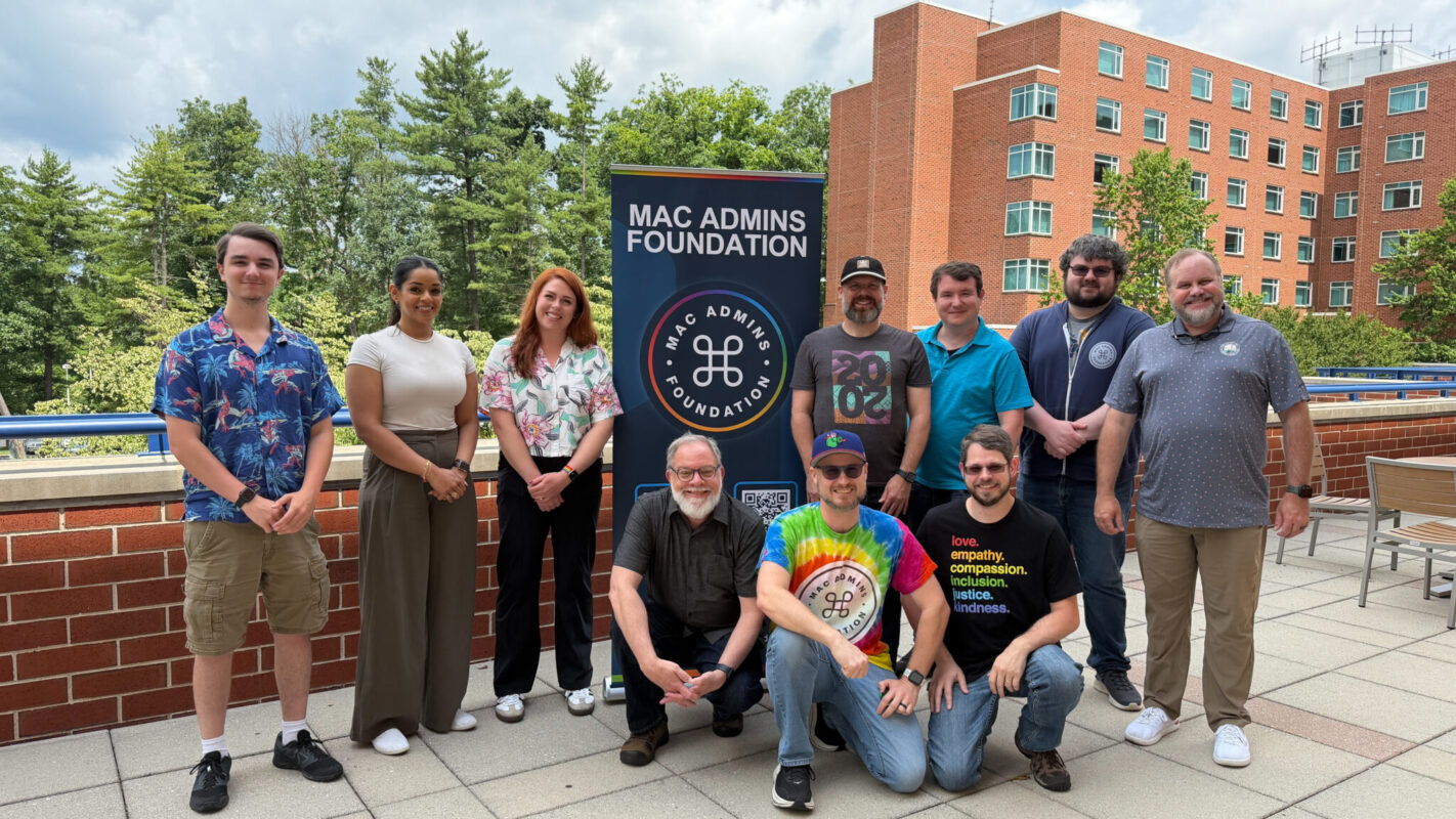 Jonathan Blasingame stands with group of students, faculty and staff on an outdoor campus terrace beside a banner for the MAC Admins Foundation.