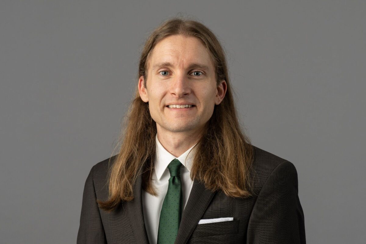 Professional headshot of Dr. Hunter Schroer wearing a black suit jacket, white shirt and green tie.