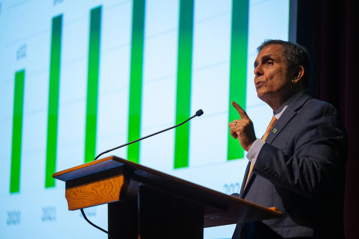 Chancellor Mo Dehghani speaks at a podium during Missouri S&T's 2025 State of the University address, with a presentation slide displaying green bar charts in the background.