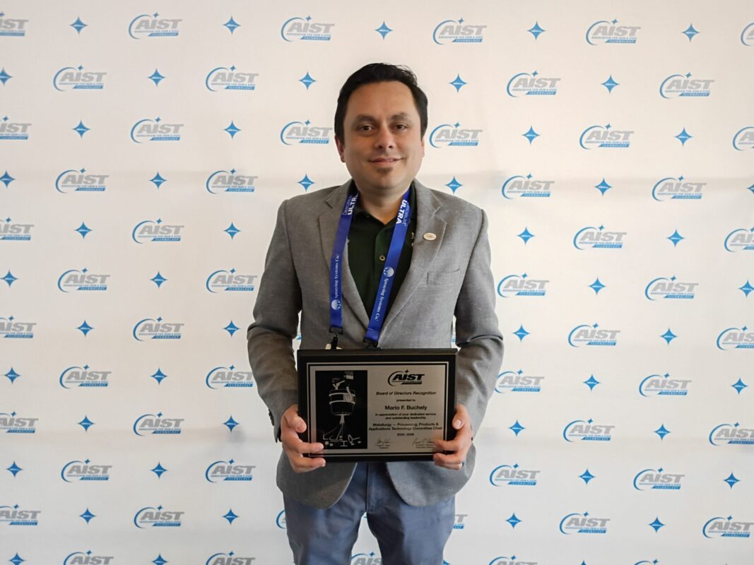 Person holding a plaque while standing in front of a CAEST-branded backdrop at an awards event.